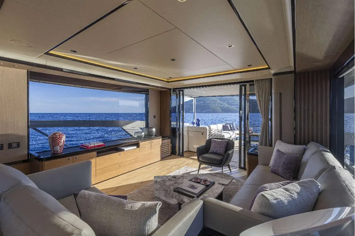 Luxurious yacht interior featuring a modern lounge, ocean view, and stylish decor, including cushions and a coffee table.